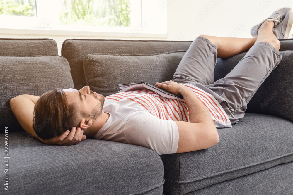Handsome man with book sleeping on sofa at home Handsome man with book sleeping on sofa at home