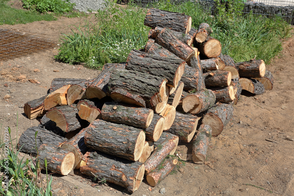 Dry firewood for firing and heating lie in a pile in the backyard Dry firewood for firing and heating lie in a pile in the backyard