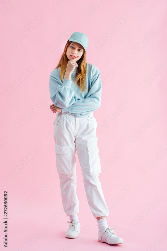 full length view of sad pretty teenage girl in cap on pink full length view of sad pretty teenage girl in cap on pink