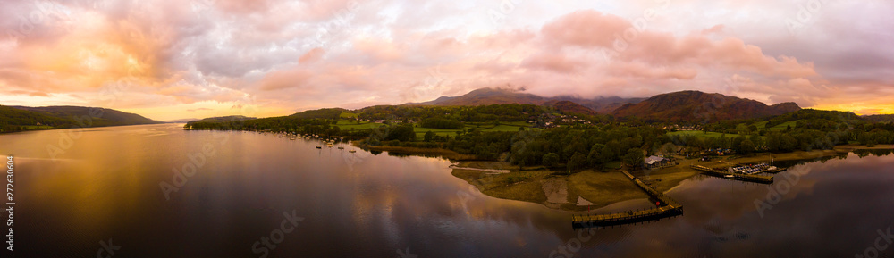 Aerial over the lake district Coniston lake during a dramatic sunrise surrounded by mountains, England panoramic