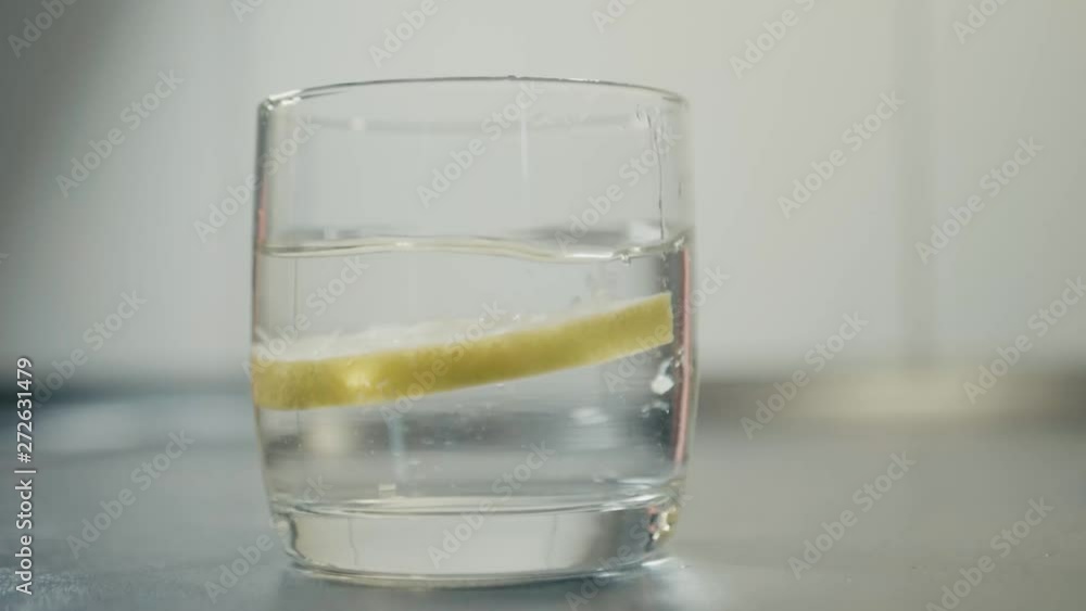 reverse lemon fall into glass of water in a kitchen. reverse lemon fall into glass of water in a kitchen.