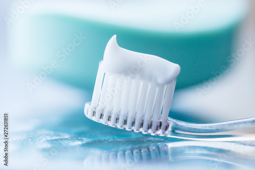 Plastic toothbrush with white toothpaste on a blue table photo