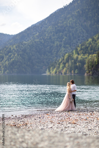 bride and groom with views of the beautiful green mountains and lake with blue water