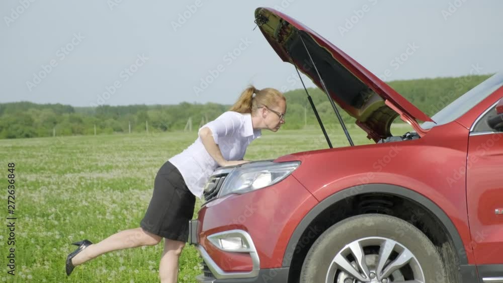 woman opens hood of car, expresses bewilderment and closes hood. woman opens hood of car, expresses bewilderment and closes hood.