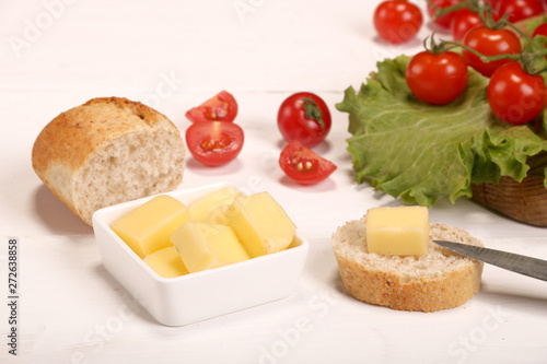 Ripe fresh Juicy organic brunch of cherry tomatoes on cutting board with Green Lettuce, bread, butter on a white table