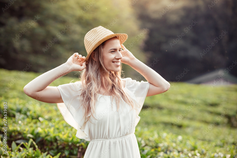Close-up portrait of a positive smiling beautiful young blonde girl in a straw hat enjoying a summer vacation in the countryside. Concept of clean air and life in the countryside