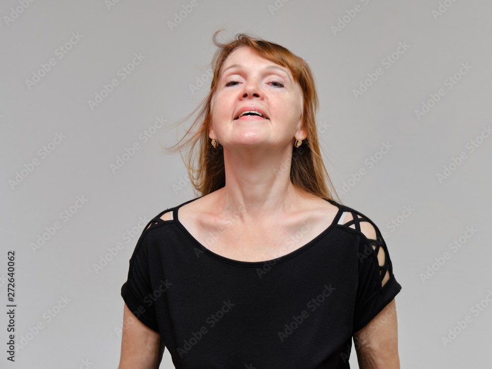 Studio portrait of a beautiful pretty woman aged 40 years on a white background, smiling, showing different emotions, happy with life. In a black sweater with red hair. Directly opposite the camera. Studio portrait of a beautiful pretty woman aged 40 years on a white background, smiling, showing different emotions, happy with life. In a black sweater with red hair. Directly opposite the camera.