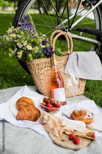 Fototapeta Naklejka Na Ścianę i Meble -  Beautiful summer picnic with strawberries, cheese and rose wine on the lawn in the city park