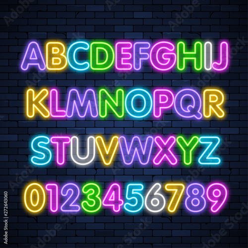 Glowing neon multicolored alphabet on brick wall background