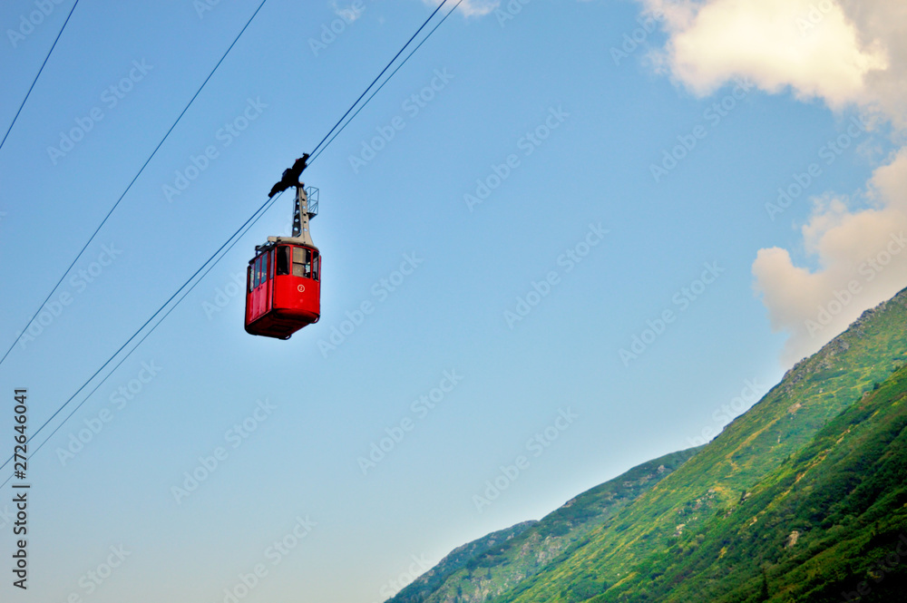 ropeway and funicular road in mountain, red cabin against a background of blue cloudy sky ropeway and funicular road in mountain, red cabin against a background of blue cloudy sky