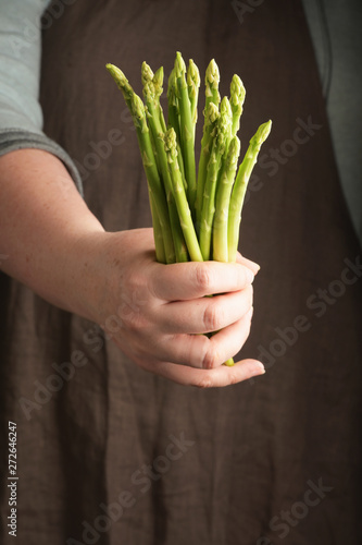 Woman holding a asparagus in hand. Rustic style. Vertical.