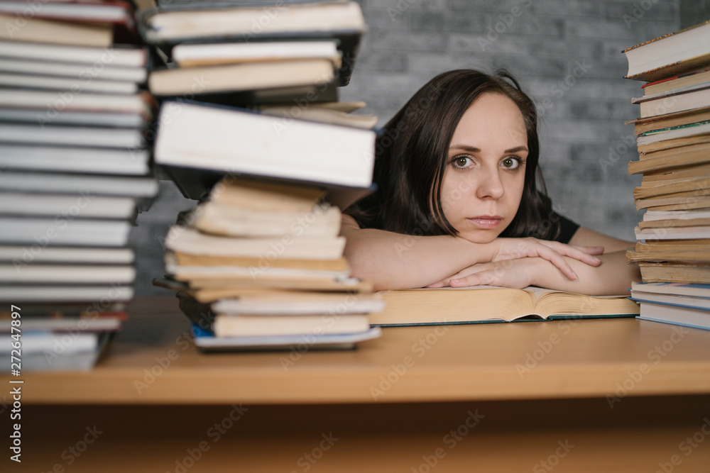 Beautiful woman student studying with a lot of paper books on the table Beautiful woman student studying with a lot of paper books on the table