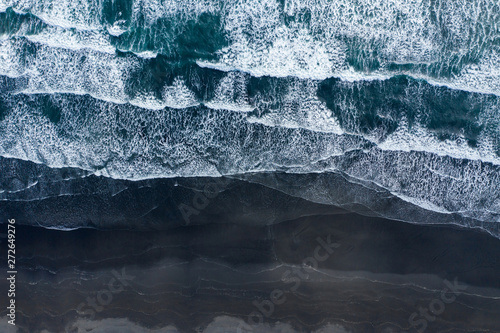 Aerial drone view of ocean waves spashing black sand beach, Iceland