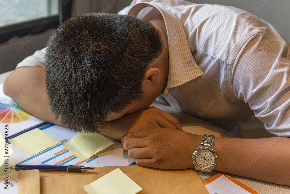 Exhausted man fall asleep on unorganized table with documents, sticky note Exhausted man fall asleep on unorganized table with documents, sticky note