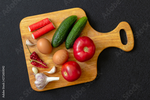 Wooden Board with vegetables on dark background