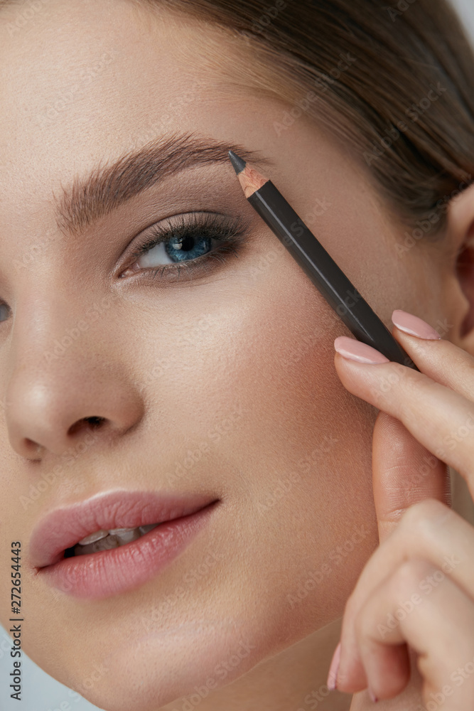 Eyebrow makeup. Beauty model shaping brows with brow pencil