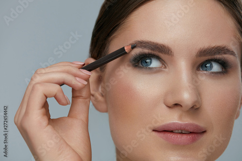Beauty makeup. Woman shaping eyebrow with brow pencil closeup photo