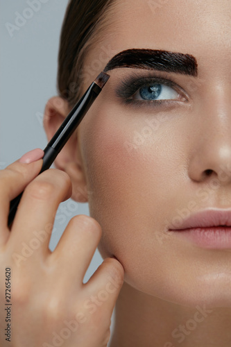 Eyebrow coloring. Woman applying brow tint with makeup brush