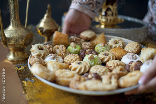 Oriental tea tray and cookies symbolising Moroccan hospitality, Islamic holidays food with decoration. Ramadan kareem. Eid mubarak. Oriental hospitality concept. Tea glasses and pot, traditional delig photo