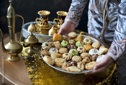 Oriental tea tray and cookies symbolising Moroccan hospitality, Islamic holidays food with decoration. Ramadan kareem. Eid mubarak. Oriental hospitality concept. Tea glasses and pot, traditional delig photo