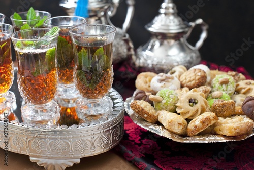 Oriental tea tray and cookies symbolising Moroccan hospitality  Islamic holidays food with decoration. Ramadan kareem. Eid mubarak. Oriental hospitality concept. Tea glasses and pot  traditional delig
