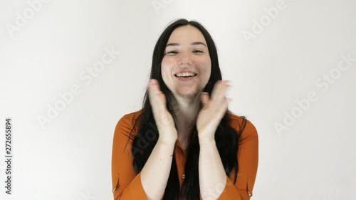 A young woman applauds. She loses herself and claps her hands. Light background