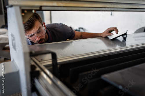 Young engineer setup plasma cutter for work in metalwork workshop.