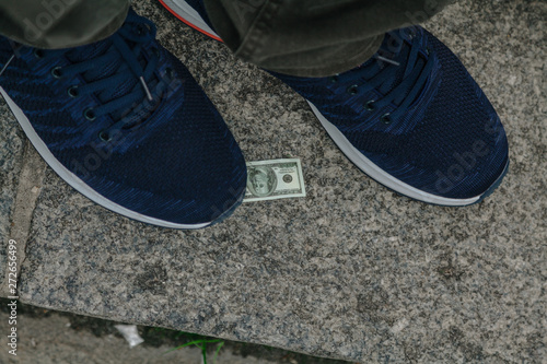 Large sneaker and small bill lie on granite step