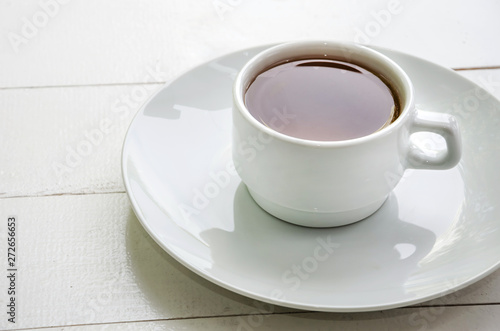 white cup of tea in a white plate on a white background, close up