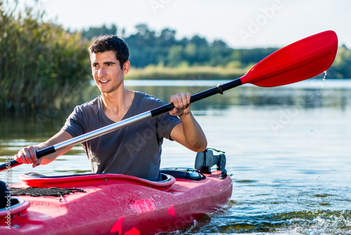 Man sitting in kayak paddling on lake