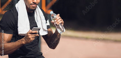 Fit Man Using Phone After Workout, Drinking Water