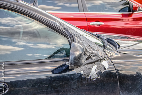 Photos Closeup of dirty car with right side mirror taped on and scratches to it and win