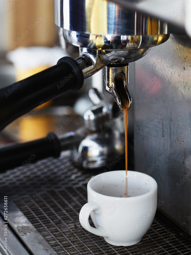 Concept shot of coffee machine in city cafe, hot espresso running into white ceramic coffee cup. Concept shot of coffee machine in city cafe, hot espresso running into white ceramic coffee cup.