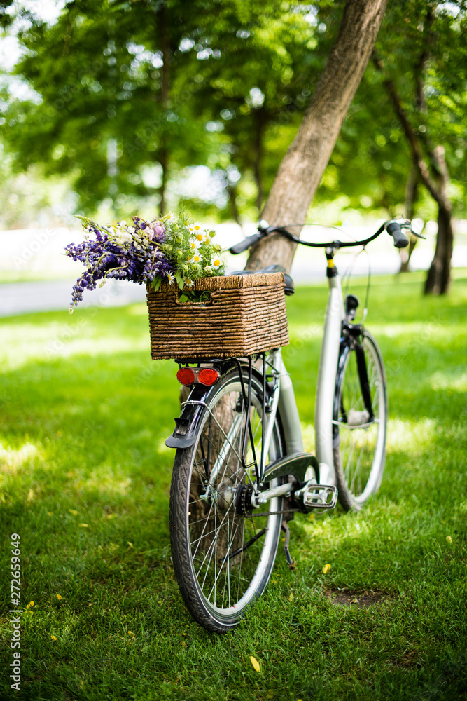 New city bicycle with bouquet of flowers in wicker basket