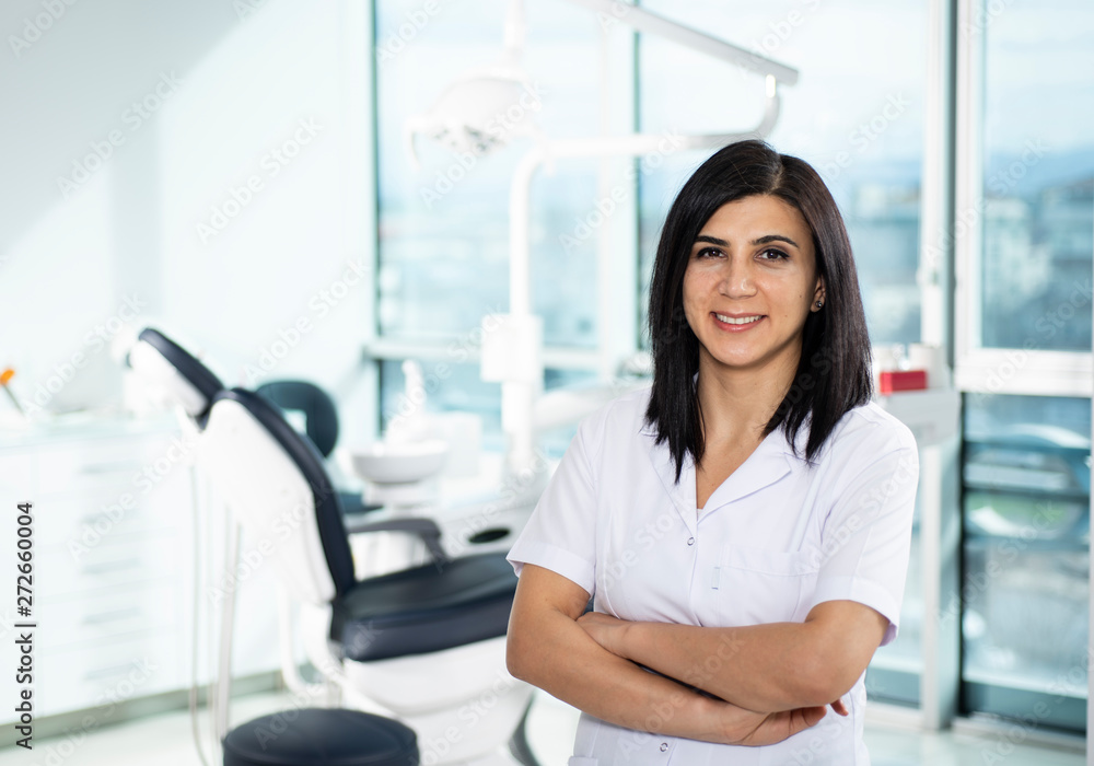 Portrait of young female dentist in white coat in practice. Space for text Portrait of young female dentist in white coat in practice. Space for text