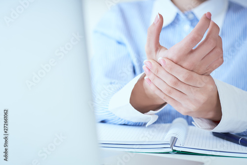 Young woman holding her wrist close-up . Pain from using computer. Office syndrome hand pain by occupational disease.