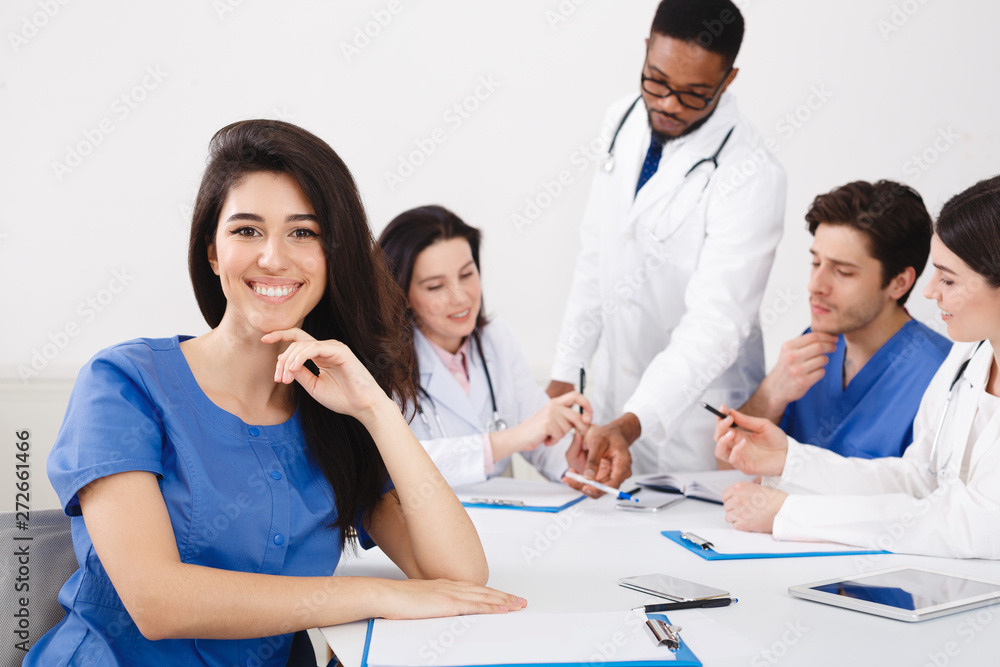 Meeting Of Medical Pros. Nurse Smiling To Camera At Meeting Meeting Of Medical Pros. Nurse Smiling To Camera At Meeting