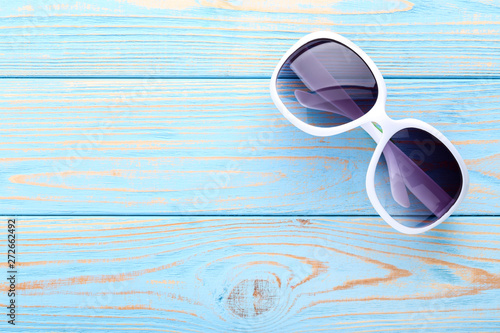 Modern sunglasses on blue wooden table
