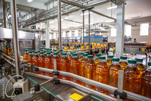 Conveyor belt with organic juice in plastic bottles on beverage plant or factory