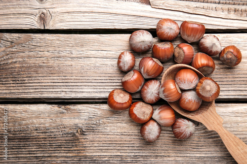 Ripe hazelnuts with spoon on brown wooden table