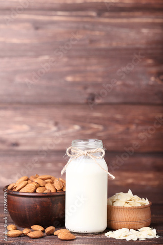 Almond and milk in bottle on brown wooden table