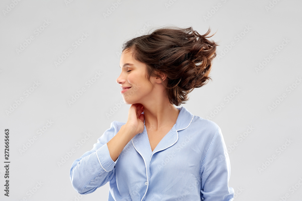 people and bedtime concept - happy young woman in pajama whipping her hair over grey background people and bedtime concept - happy young woman in pajama whipping her hair over grey background