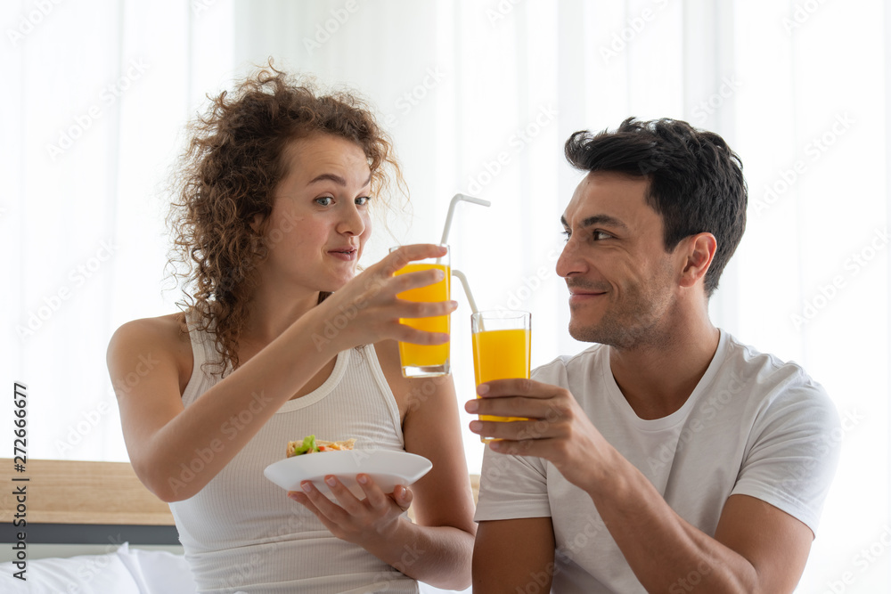 Happy couples relaxing in the white bedroom Of the apartment With various emotions With snacks, coffee, fruit in the morning Happy couples relaxing in the white bedroom Of the apartment With various emotions With snacks, coffee, fruit in the morning