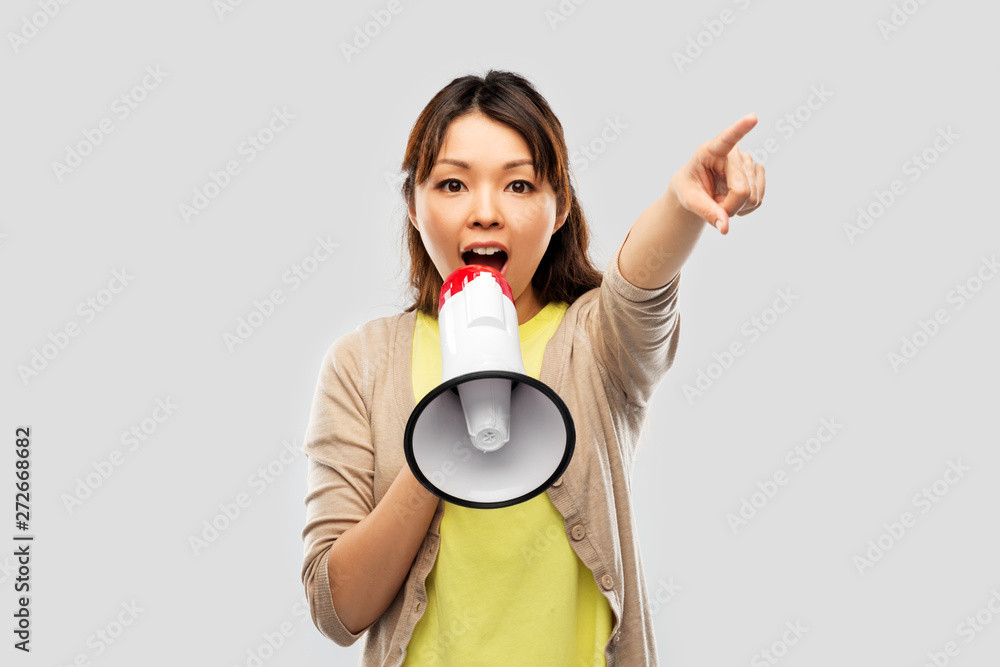 communication, feminism and human rights concept - asian young woman speaking to megaphone over grey background communication, feminism and human rights concept - asian young woman speaking to megaphone over grey background