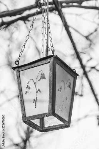 Old retro lantern with a pattern hanging on a chain in the garden.