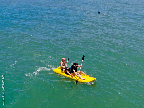 Aerial view of strong young active men kayaking on the clear blue  turquoise water of the ocean. Active vacation. Praia do Forte, Brazil © Unwind
