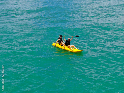 Aerial view of strong young active men kayaking on the clear blue turquoise water of the ocean. Active vacation. Praia do Forte, Brazil