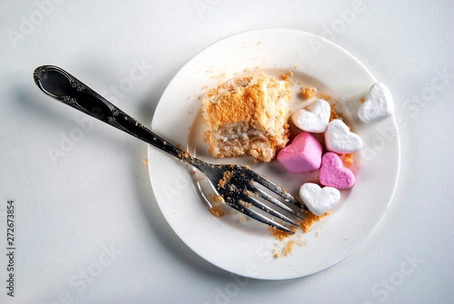  White and pink heart-shaped marshmallows lie on a saucer. Unfinished cake. View from above.