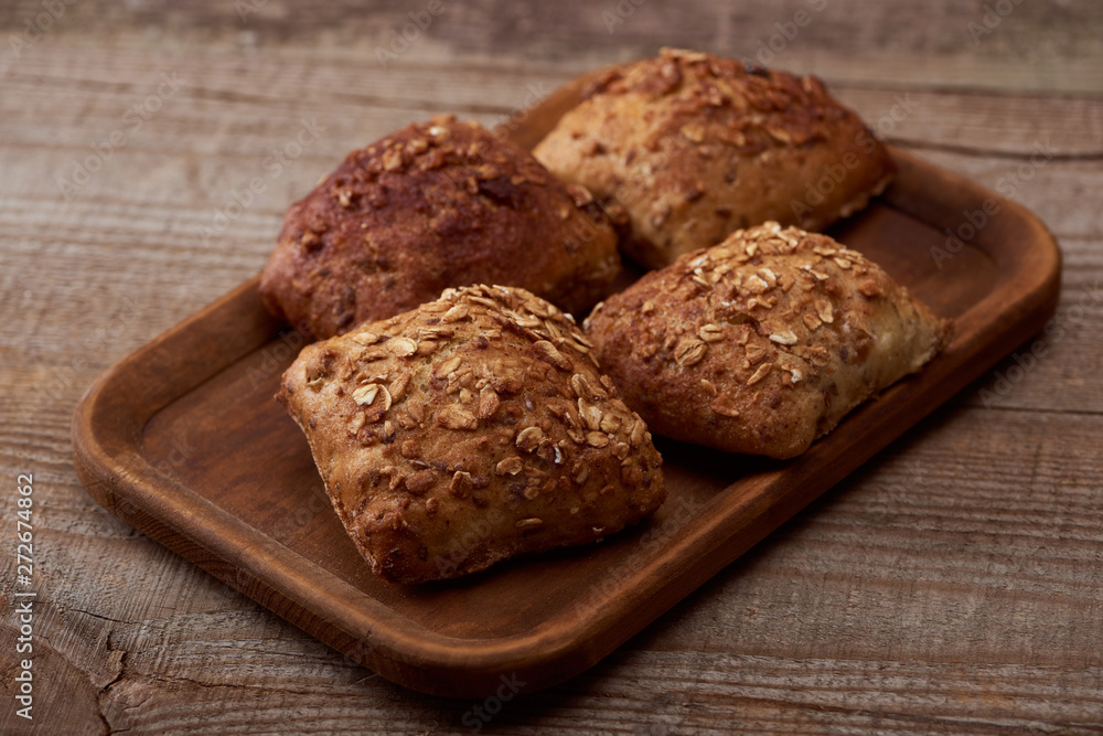 fresh baked buns with grains on wooden board on rustic table