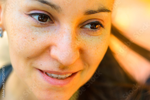 Outdoor portrait of smiling young woman with brown eyes close-up